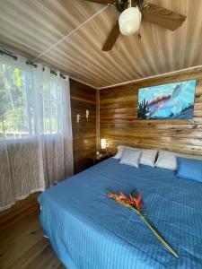 1 dormitorio con 1 cama azul y ventilador de techo en Ponci’s Gate to Gaia Holistic Center en Bocas Town