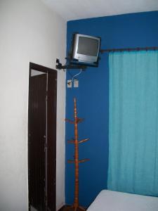 a bedroom with a tv on a blue wall at Hotel Madrid in Mendes