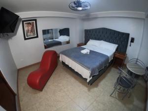 1 dormitorio con 1 cama y 1 silla roja en Hostal DRABA en Lima