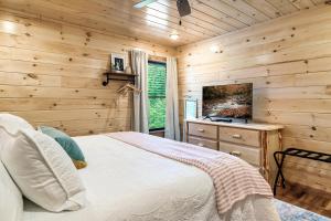 SmokiesBoutiqueCabins would love to host you at Dolly's Cute Cabin! 4 Suites with Private Bathrooms - Hot Tub, Fire Pit, Game Room, Resort Pool open Memorial Day through Labor Day! في غاتلينبرغ: غرفة نوم بسرير وجدار خشبي
