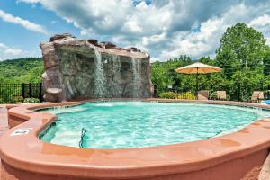 a swimming pool with a waterfall in a resort at SmokiesBoutiqueCabins would love to host you at Dolly's Cute Cabin! 4 Suites with Private Bathrooms - Hot Tub, Fire Pit, Game Room, Resort Pool open Memorial Day through Labor Day! in Gatlinburg