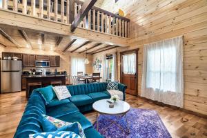 SmokiesBoutiqueCabins would love to host you at Dolly's Cute Cabin! 4 Suites with Private Bathrooms - Hot Tub, Fire Pit, Game Room, Resort Pool open Memorial Day through Labor Day! في غاتلينبرغ: غرفة معيشة مع أريكة زرقاء وطاولة