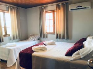 een slaapkamer met 2 bedden en handdoeken bij Casa 2 Chalé Alto dos Bandeirantes-Tiradentes in Tiradentes
