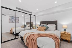 1 dormitorio con 2 camas y un espejo grande en Designer Apartment - giant terrace - city location, en Hobart