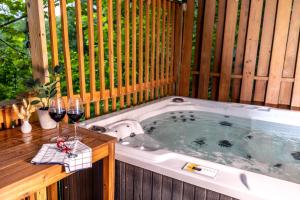 a hot tub with glasses of wine and a table with glasses of wine at SmokiesBoutiqueCabins would love to host you! 4 miles to Gatlinburg Strip! Resort Pool open May 1 through Oct 1! Views, Shuffleboard, Hot Tub, Arcade! in Gatlinburg