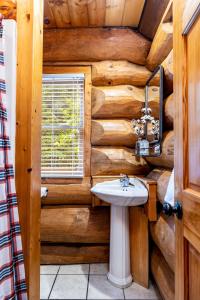 a bathroom in a log cabin with a sink at SmokiesBoutiqueCabins would love to host you! 4 miles to Gatlinburg Strip! Resort Pool open May 1 through Oct 1! Views, Shuffleboard, Hot Tub, Arcade! in Gatlinburg