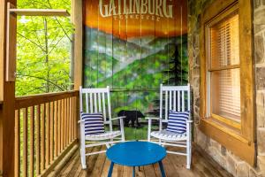 two chairs and a table on a porch at SmokiesBoutiqueCabins would love to host you! 4 miles to Gatlinburg Strip! Resort Pool open May 1 through Oct 1! Views, Shuffleboard, Hot Tub, Arcade! in Gatlinburg