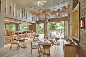 un restaurante con mesas y sillas de madera y ventanas en Villa La Casa 2 BR, en Uluwatu