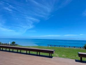 two benches sitting on a deck looking at the ocean at Noosa海岸行館 in Fengbin