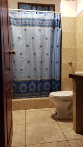 a bathroom with a blue shower curtain and a toilet at Valles de Olon, Lugar encantador y acogedor para un feliz descanso. in Santa Elena