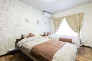 2 camas en un dormitorio con ventana en Lexia Nishikujo - Vacation STAY 15380, en Osaka