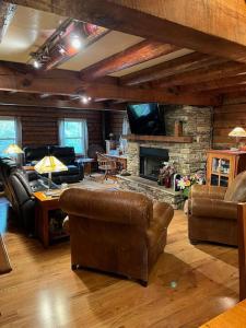 sala de estar con muebles de cuero y chimenea de piedra. en Acorn Resort a Unique Retreat Cabin, 13 acres land, en Bloomington