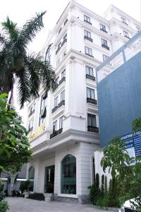 a white building with a palm tree in front of it at Grand Hill Hotel & Apartment in Hai Phong