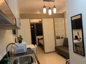 a kitchen with a sink and a living room at SHORE RESIDENCE D18 shortwalk Mall of asia near airport in Manila