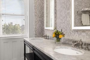 a bathroom with two sinks and a vase of flowers at Hamilton Turner Inn in Savannah