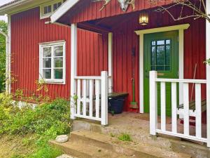 a red house with a green door and a white fence at 6 person holiday home in LOFTAHAMMAR-By Traum in Loftahammar