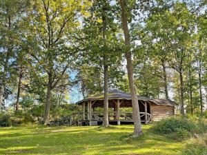 una cabaña de madera en medio de un campo con árboles en Holiday home Vingåker III en Vingåker