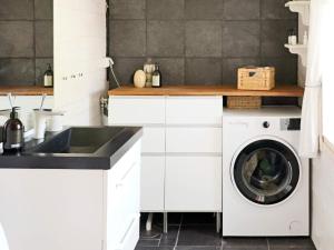 a white kitchen with a washing machine and a sink at Holiday home HISHULT III in Hishult
