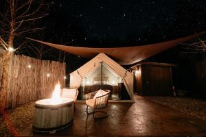 a tent with a table and chairs in front of it at night at Cozy Unique Glamping on 53 acres - Bedrock Site in Branson