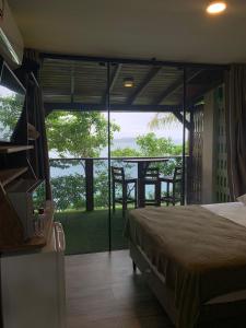 a bedroom with a bed and a balcony with a view at Paraíso das Tartarugas in Bombinhas