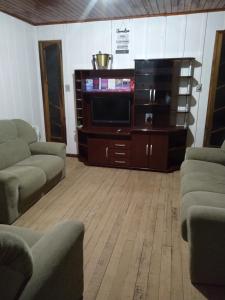 ein Wohnzimmer mit 2 Sofas und einem TV in der Unterkunft Casa de madeira em local tranquilo in Mafra