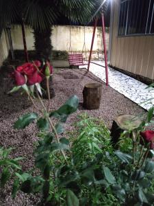 einen Garten mit roten Blumen und einer Schaukel in der Unterkunft Casa de madeira em local tranquilo in Mafra