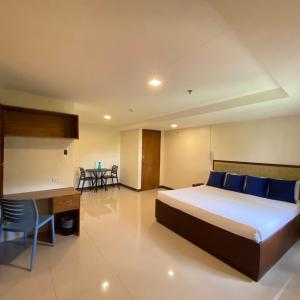 a bedroom with a bed and a desk and chairs at Suntal Residences in Bacolod