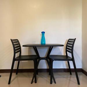 巴科洛德的住宿－Suntal Residences，一张桌子,上面有两把椅子和一个蓝色的花瓶
