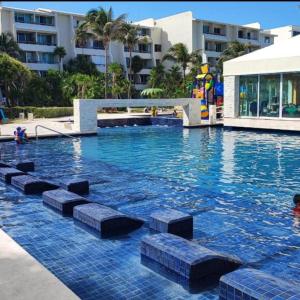 een zwembad met blauw water in een resort bij Solymar hermoso apartamento in Cancun