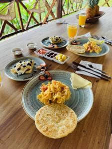 - une table en bois avec des assiettes de nourriture pour le petit-déjeuner dans l'établissement Eco Glamping Cordillera, à Buenavista