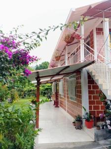 a brick building with a porch with flowers on it at La Ramada Campestre in Calarcá