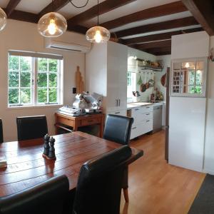 a dining room with a table and a kitchen at Abbeygate Cottage in Auckland