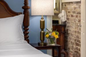 a bed with a lamp and a vase of flowers on a table at Hamilton Turner Inn in Savannah