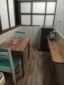 a wooden table with chairs and a lamp and windows at Chom Suan Farmstay in Ko Kood