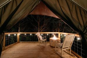 dos sillas y una mesa en una terraza por la noche en Treehouse Cozy Glamping Site en Branson