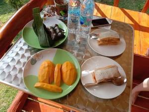 una mesa con platos de pan y fruta. en Mookanda bungalow, en Ko Yao Noi