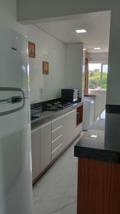 a large kitchen with white counters and a refrigerator at Encantador Apto NOVO, climatizado e confortável - 200m das Thermas in Piratuba