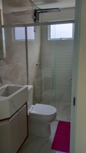 y baño con aseo, lavabo y ducha. en Encantador Apto NOVO, climatizado e confortável - 200m das Thermas en Piratuba