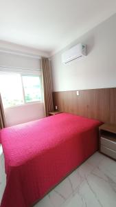 1 dormitorio con 1 cama rosa grande y ventana en Encantador Apto NOVO, climatizado e confortável - 200m das Thermas en Piratuba