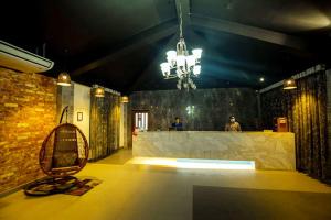um quarto com um bar com um banco e um lustre em Shaira Garden Hotel & Resorts em Nārāyanganj