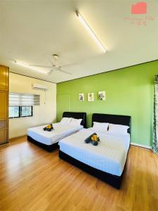 Cette chambre comprend 2 lits dans une chambre dotée de murs verts et de parquet. dans l'établissement VQ-villa1, à Kota Kinabalu