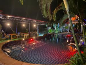 a swimming pool at night with tables and a palm tree at Krabi Villa Phu Khao Private Resort in Klong Muang Beach