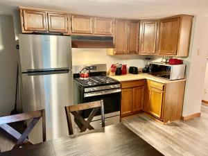 uma cozinha com armários de madeira e um frigorífico de aço inoxidável em Convenient 2BR/3BD pet friendly Apartment with private entrance em Chicopee