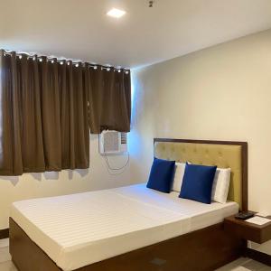 a bedroom with a large bed with blue pillows at Suntal Residences in Bacolod