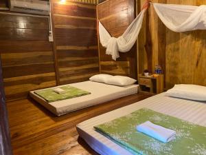 two beds in a room with wooden walls at Hồng Gấm Homestay in Bak Kan