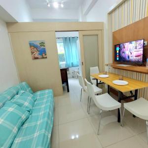 Cette chambre comprend un lit, une table et une télévision. dans l'établissement Sea Residences by Jan & Val Alano, à Manille