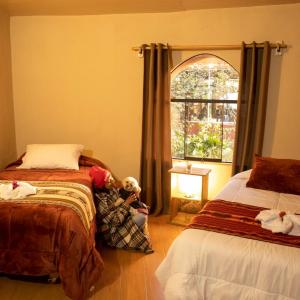 um quarto com 2 camas e uma janela com um animal de peluche em Valle Andino Lodge em Urubamba