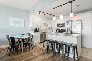 a kitchen with white cabinets and a table and chairs at Luxurious 4 Bedroom Condo! Gulf Views! Sleeps 10 & Easy Beach Access! by Dolce Vita Getaways PCB in Panama City Beach