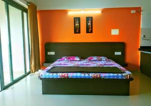 a bed in a room with an orange wall at Infinity Lake View Studio in Lavasa