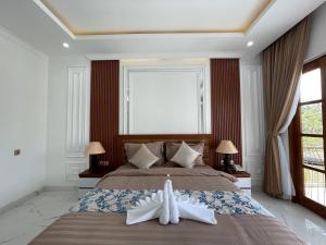 a bedroom with a large bed with a robe on it at Royal Maharani Payogan in Ubud